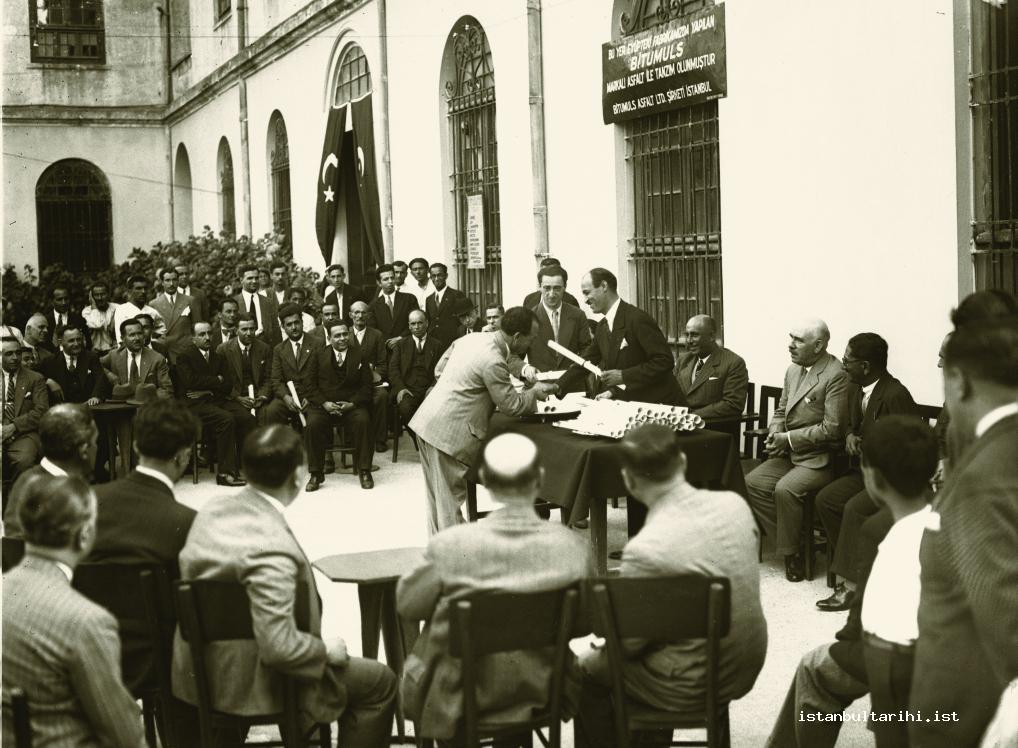 8- The famous perfume industrialist of the time Evliyazade Nurettin while getting his certi cate from Cevdet Kerim İncedayı in the exhibition of domestic goods in Galatasaray High School in 1930 (IBB Kültür A.Ş.)